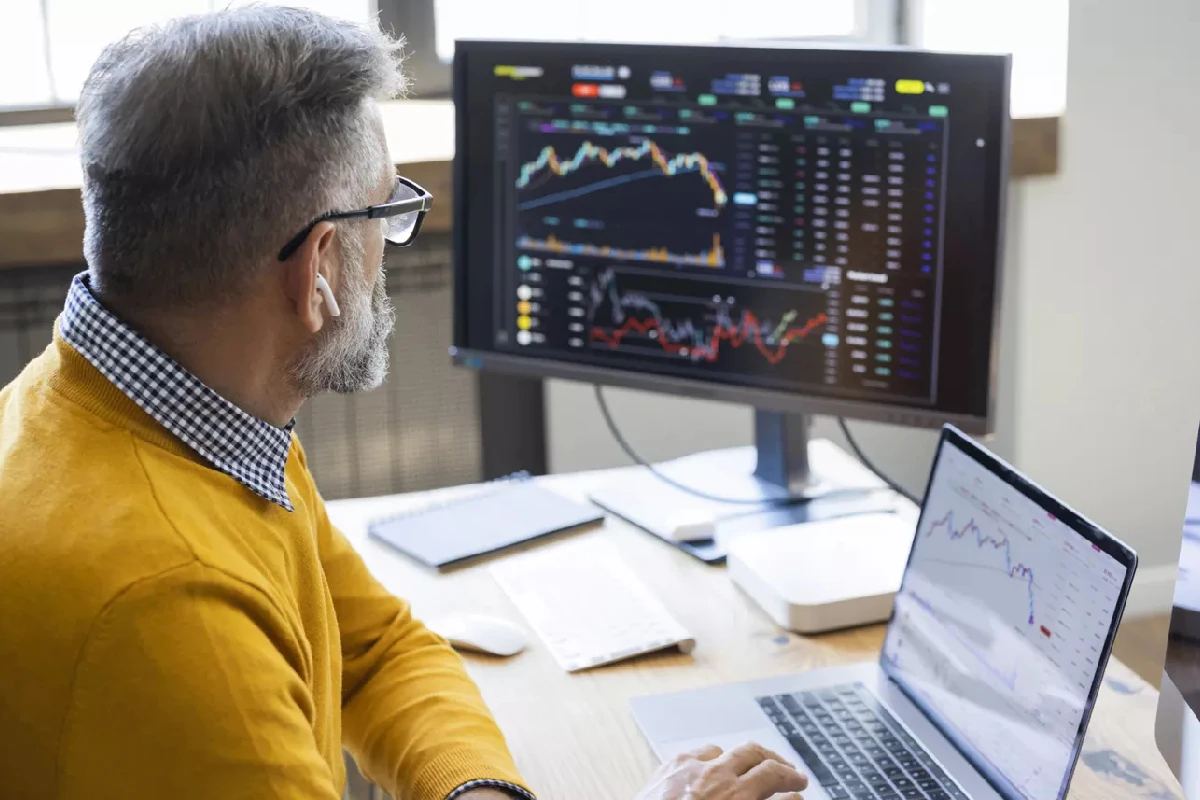 Inversionista y trader frente a pantalla mostrando gráficos